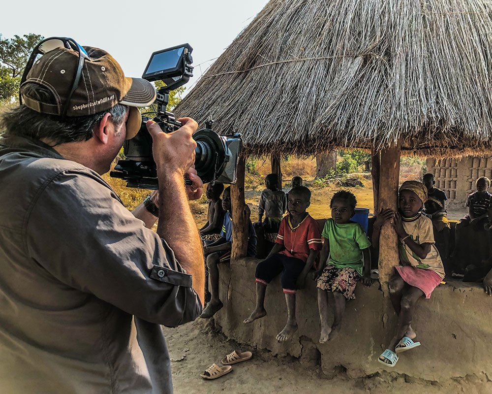 Filming children in front of a thatched-roof hut in Zambia for the film Killing the Shepherd.