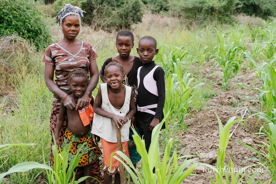 Woman and children standing in a field in Zambia with greenery around